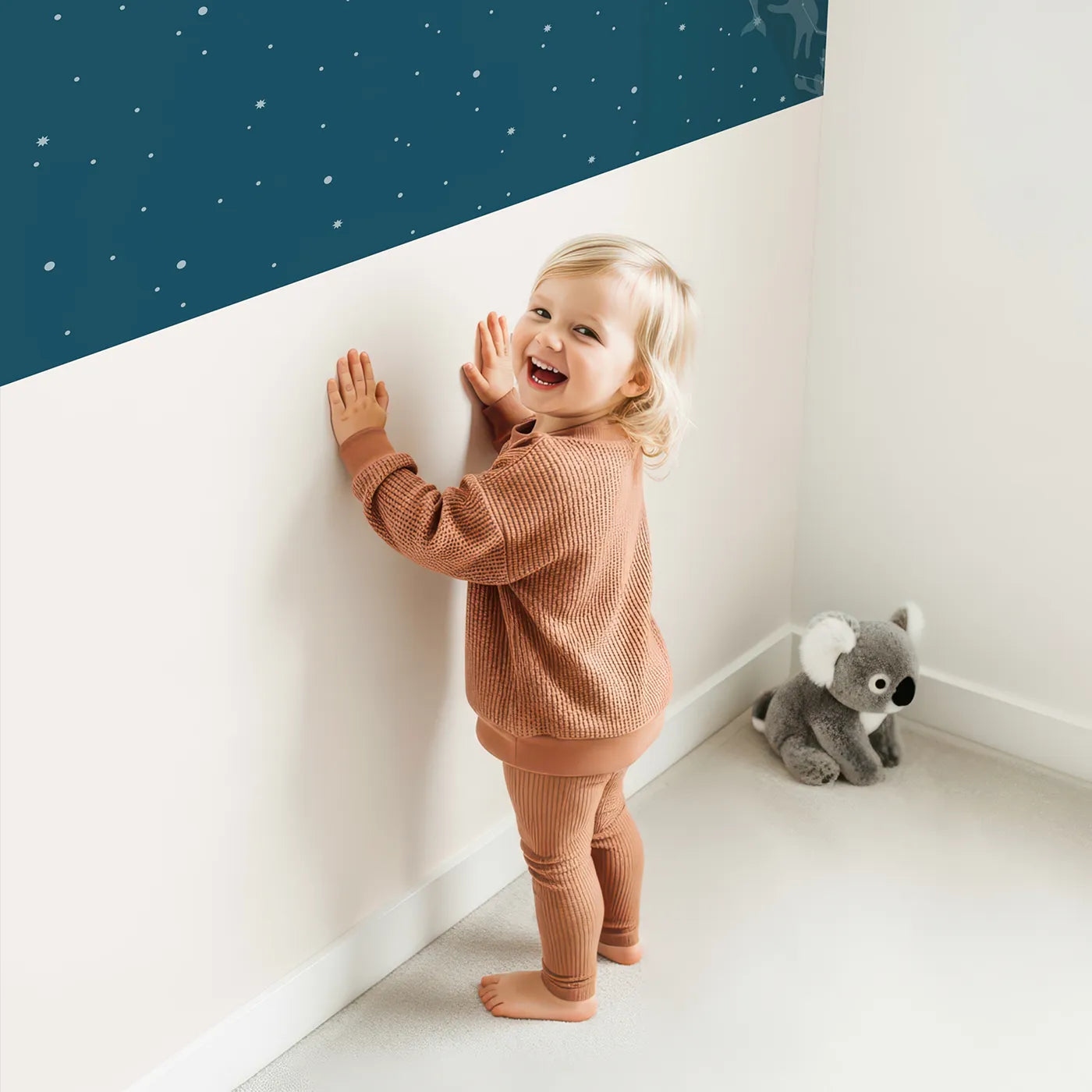Child in front of Whimsy Tots Animal Constellations Wall Mural with animal, star, constellation, space, night, bear, lion, whale in design.