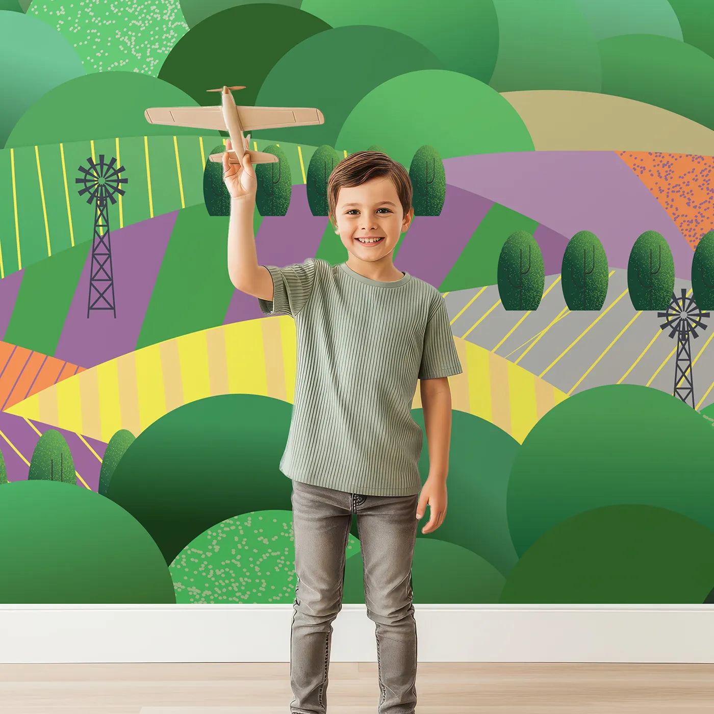 Child in front of Whimsy Tots Rolling Hills Farm Wall Mural with farm, countryside, hill, windmill, landscape, green, modern, field in design.
