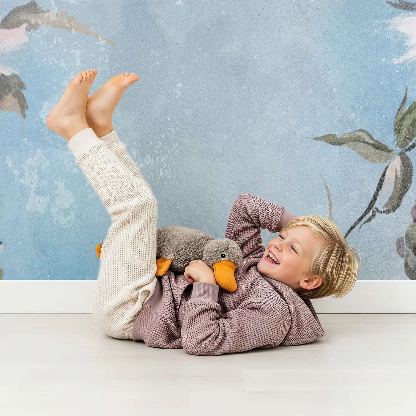 Child in front of Whimsy Tots Faded Blue Floral Wall Mural with flower, floral, vintage, blue, pink, grunge, distressed, painterly in design.