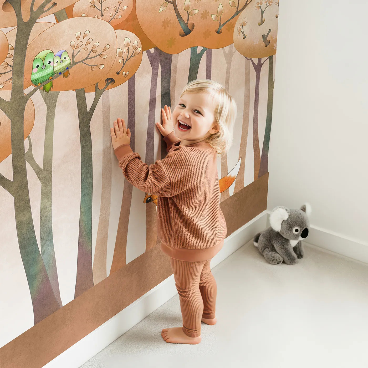 Child in front of Whimsy Tots Whimsical Autumn Forest Wall Mural with forest, autumn, fox, bird, cute, whimsical, orange, tree in design.