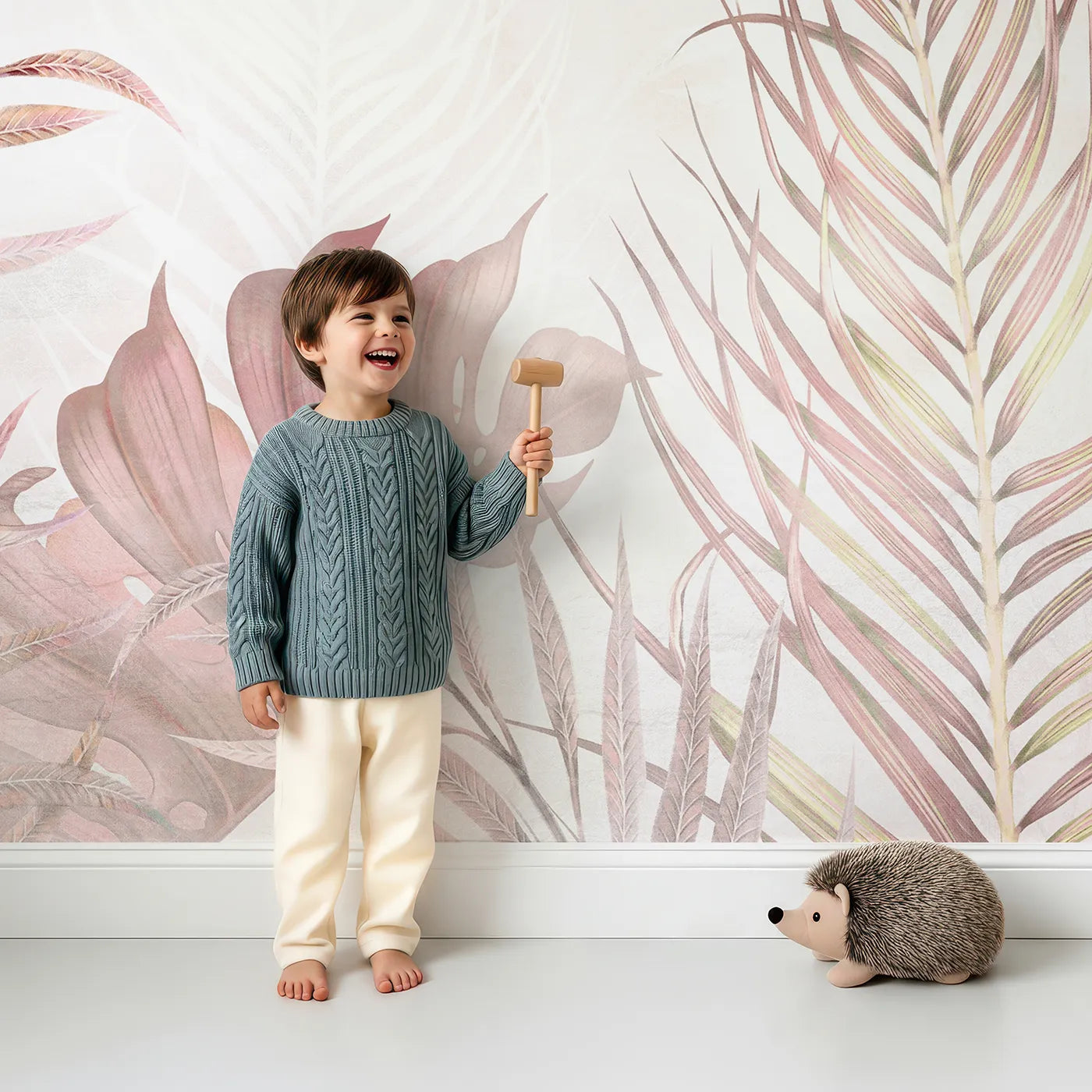Child in front of Whimsy Tots Pastel Tropical Leaves Wall Mural with tropical, leaf, pastel, pink, beige, jungle, modern, flower in design.