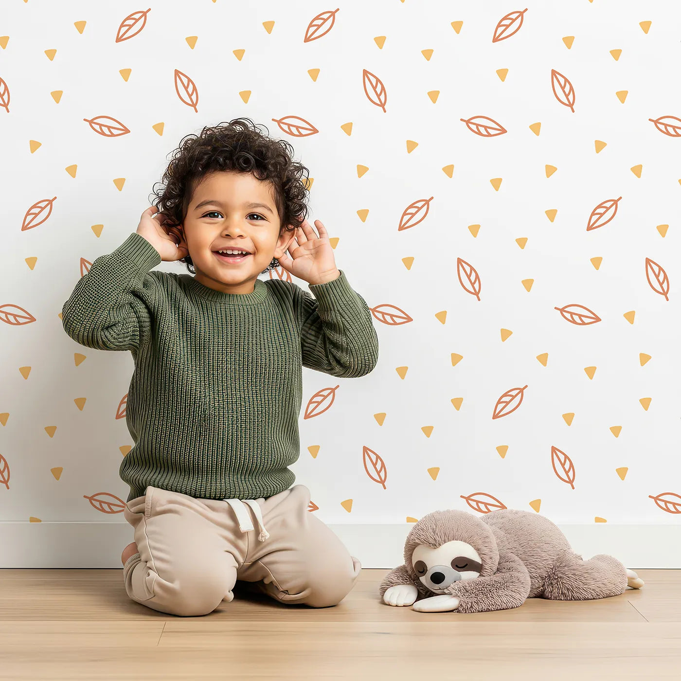 Lovely child standing in front of Whimsy Tots Autumn Leaf Scatter Wallpaper in Orange with leaf, autumn, triangle, minimalist, geometric in design.