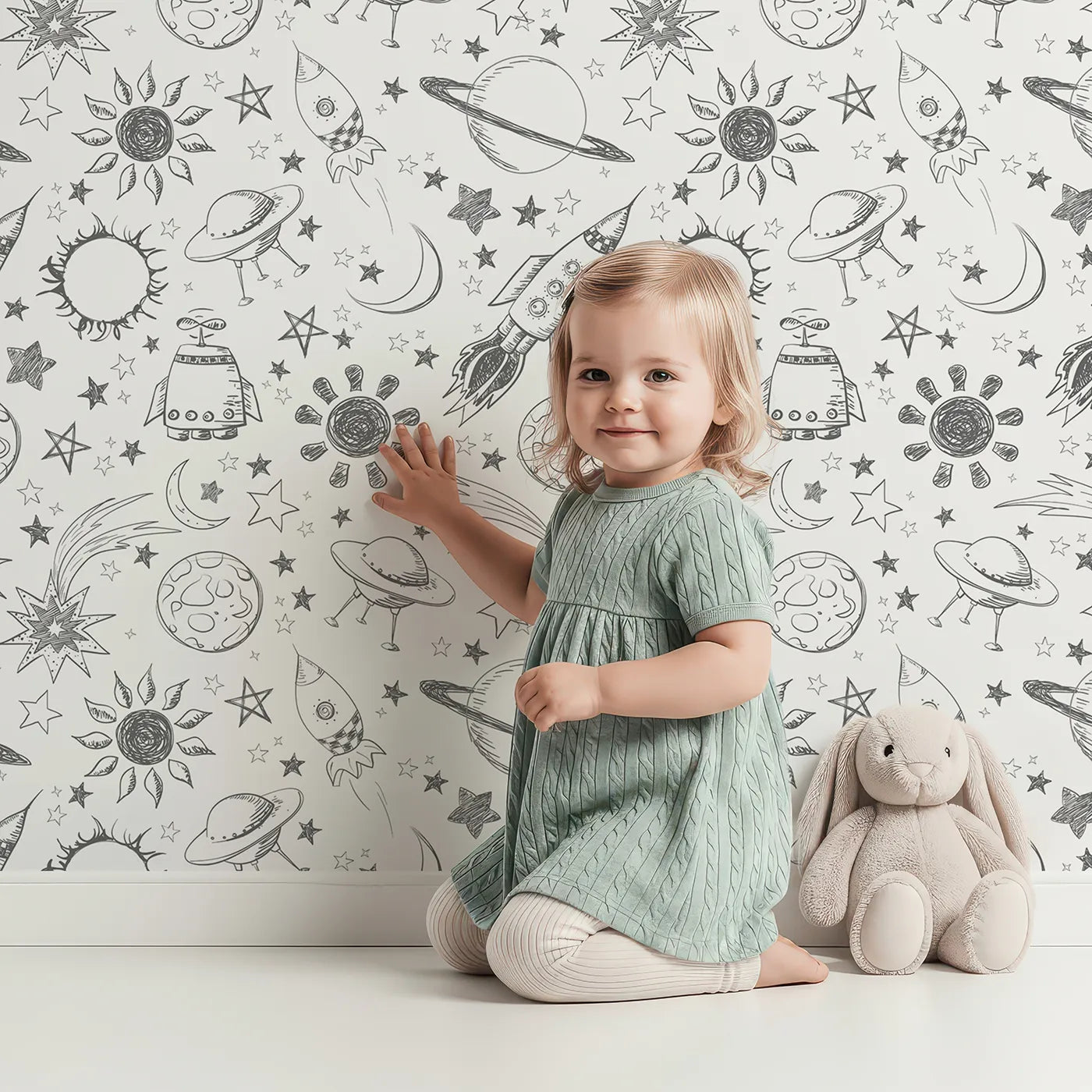 Lovely child standing in front of Whimsy Tots Space Doodle Galaxy Wallpaper with space, rocket, planet, star, doodle in design.