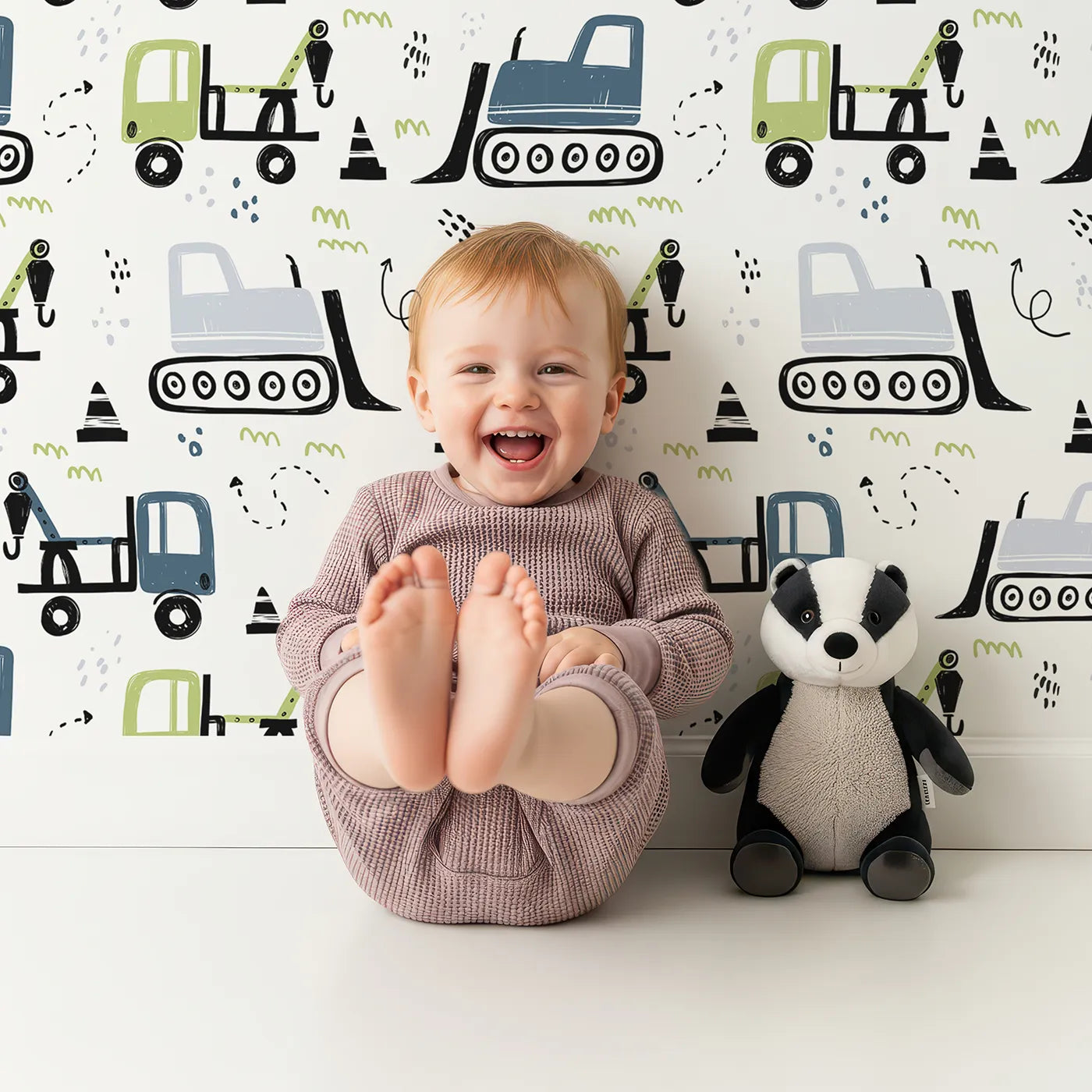 Lovely child standing in front of Whimsy Tots Construction Doodle Zone Wallpaper in Green with construction, truck, bulldozer, crane, doodle in design.