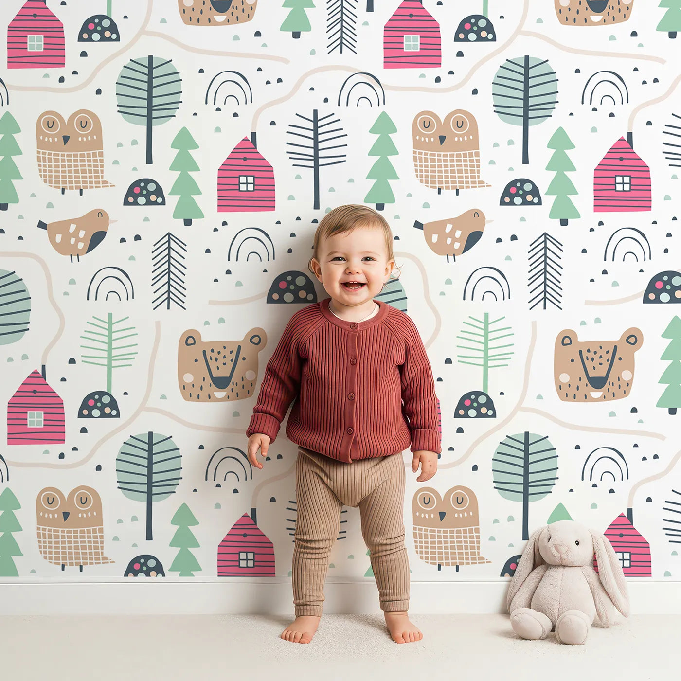 Lovely child standing in front of Whimsy Tots Woodland Village Path Wallpaper with woodland, village, house, bear, owl in design.