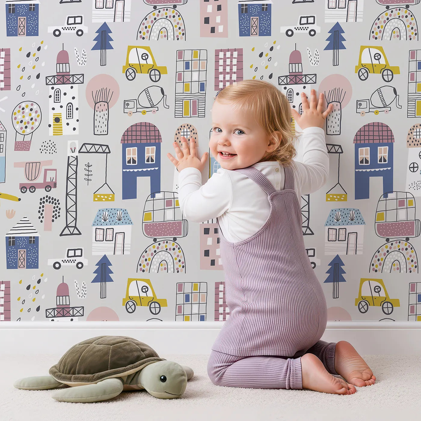 Lovely child standing in front of Whimsy Tots Busy Scandi Town Wallpaper with city, house, car, construction, town in design.