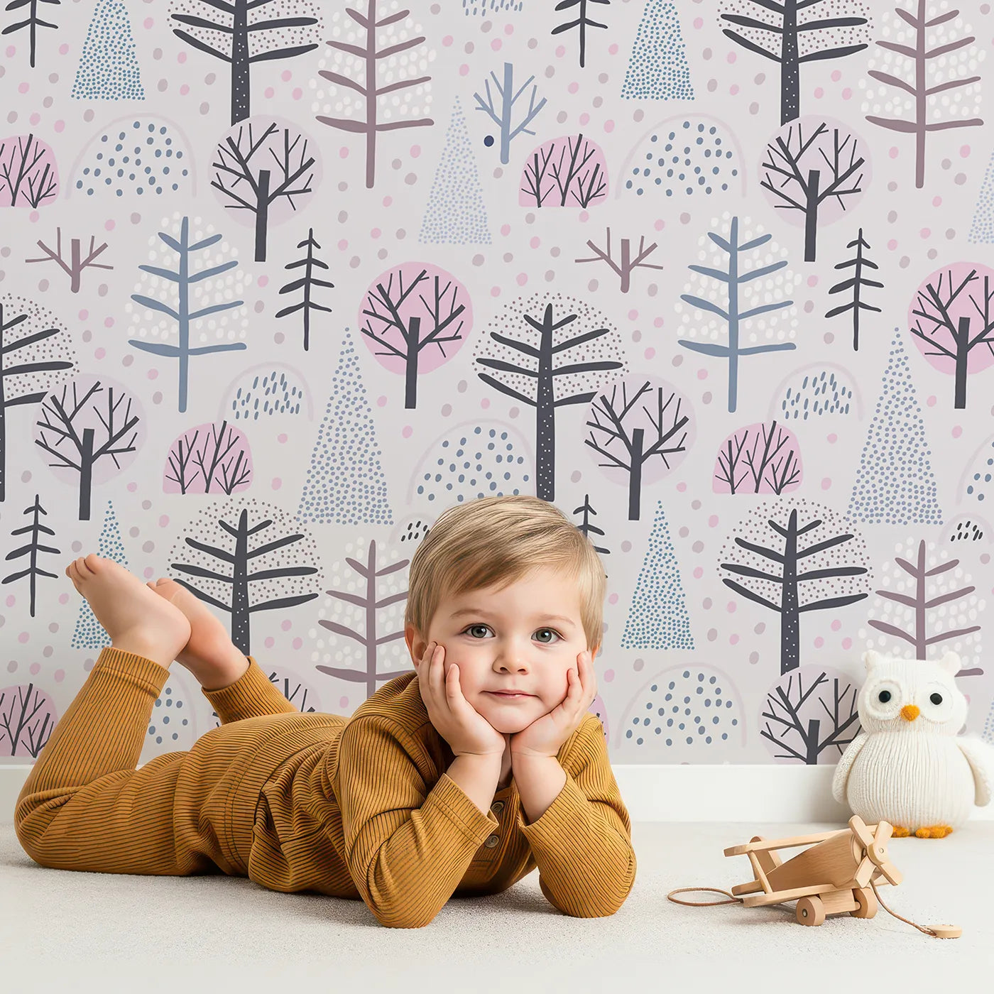 Lovely child standing in front of Whimsy Tots Dotted Winter Woods Wallpaper in Pink with forest, tree, winter, abstract, dot in design.