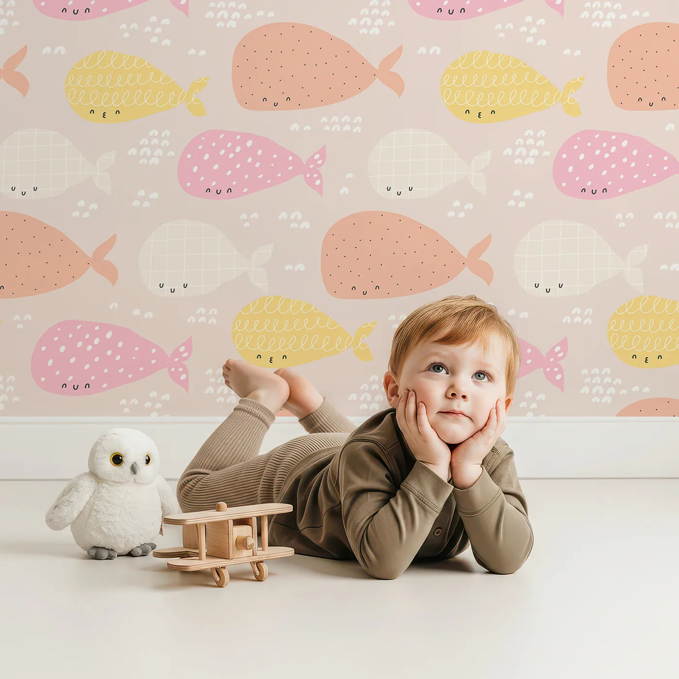 Lovely child standing in front of Whimsy Tots Pastel Whale Pod Wallpaper with whale, ocean, sea, pastel, cute in design.