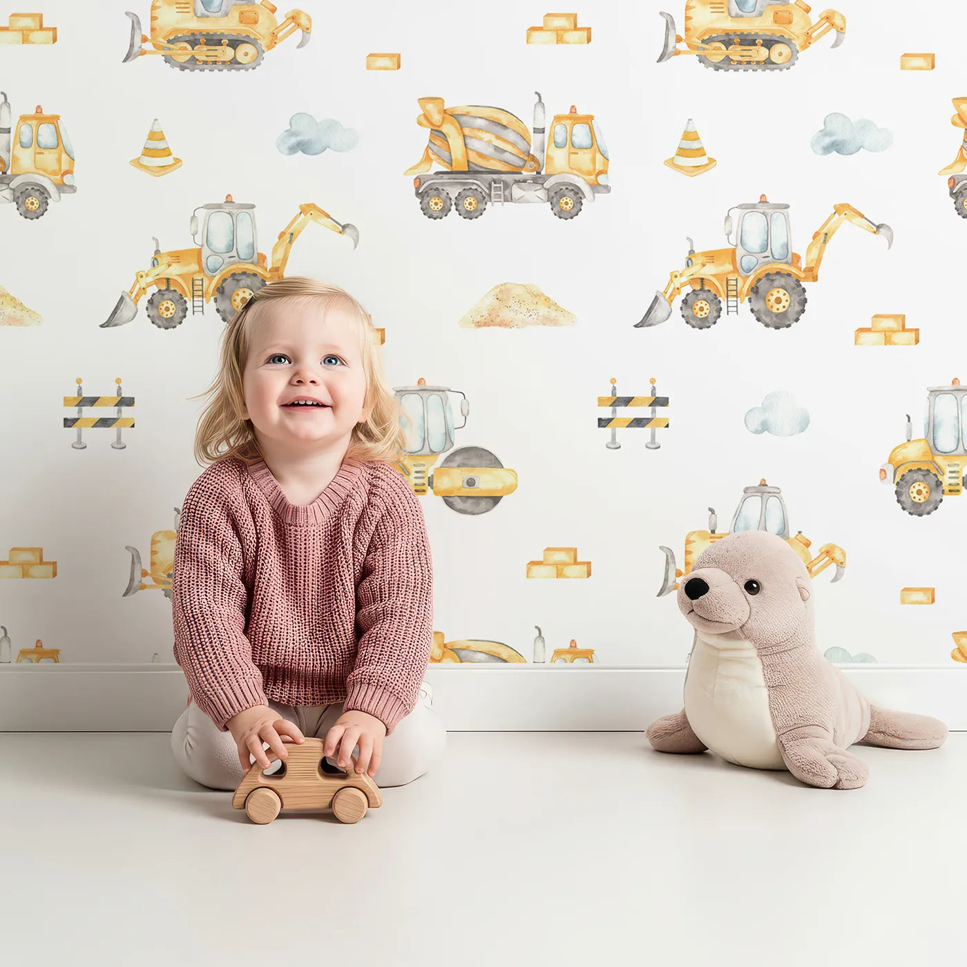 Lovely child standing in front of Whimsy Tots Watercolor Construction Zone Wallpaper with construction, truck, watercolor, bulldozer, excavator in design.