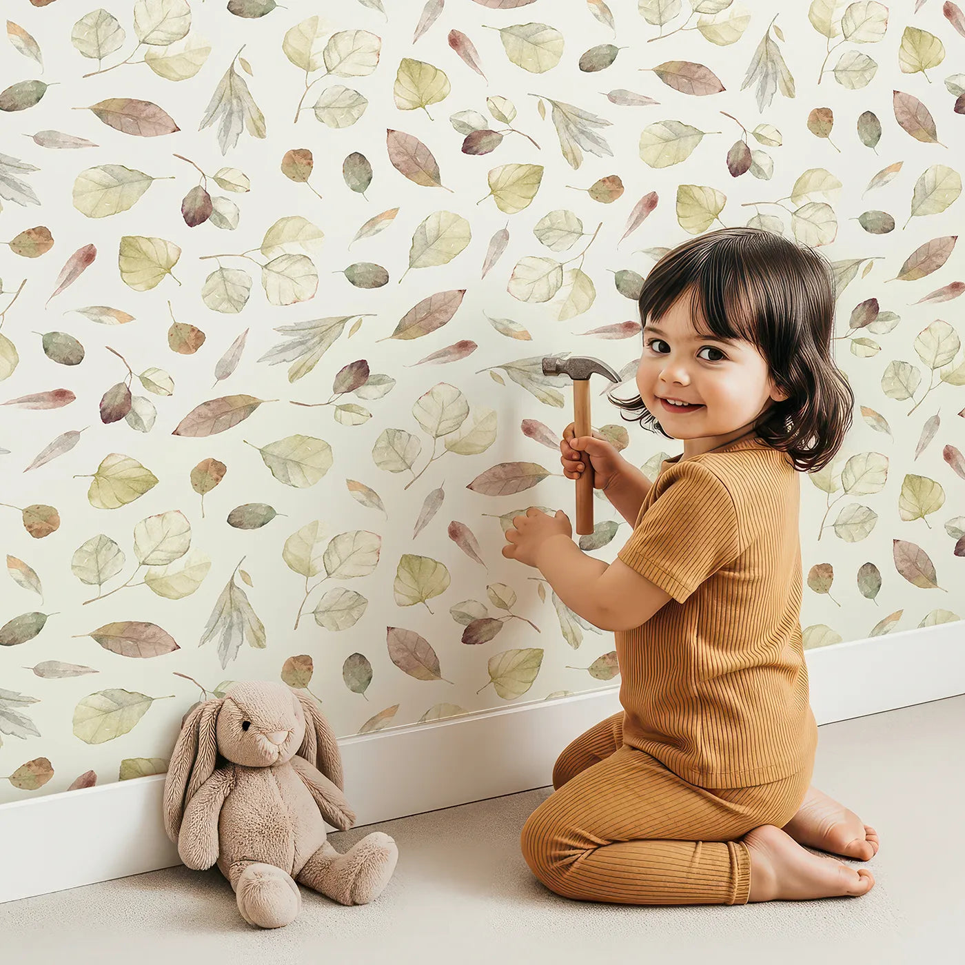 Lovely child standing in front of Whimsy Tots Faded Autumn Leaves Wallpaper with leaf, autumn, watercolor, botanical, neutral in design.
