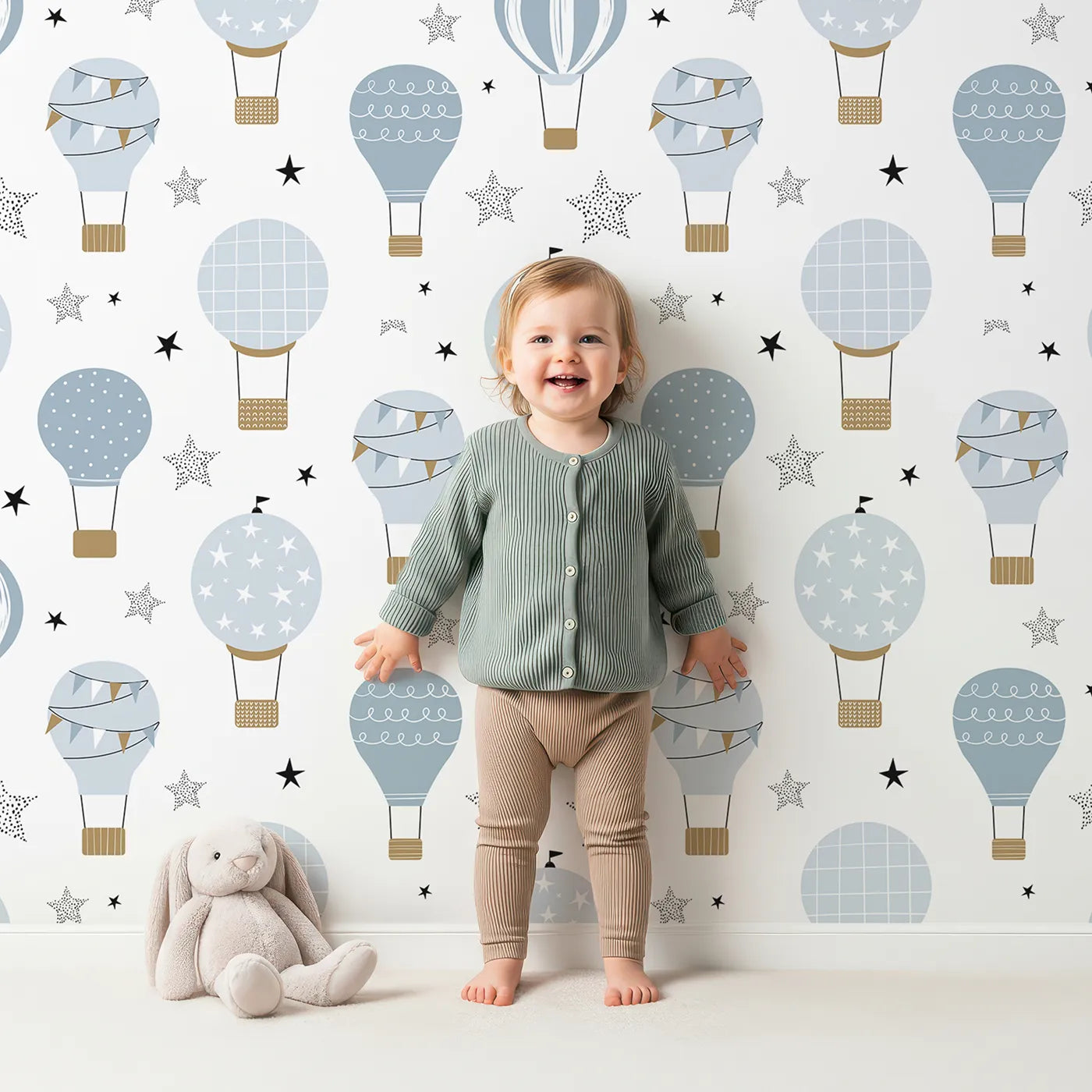 Lovely child standing in front of Whimsy Tots Blue Hot Air Balloon Festival Wallpaper with hot air balloon, sky, star, adventure, blue in design.