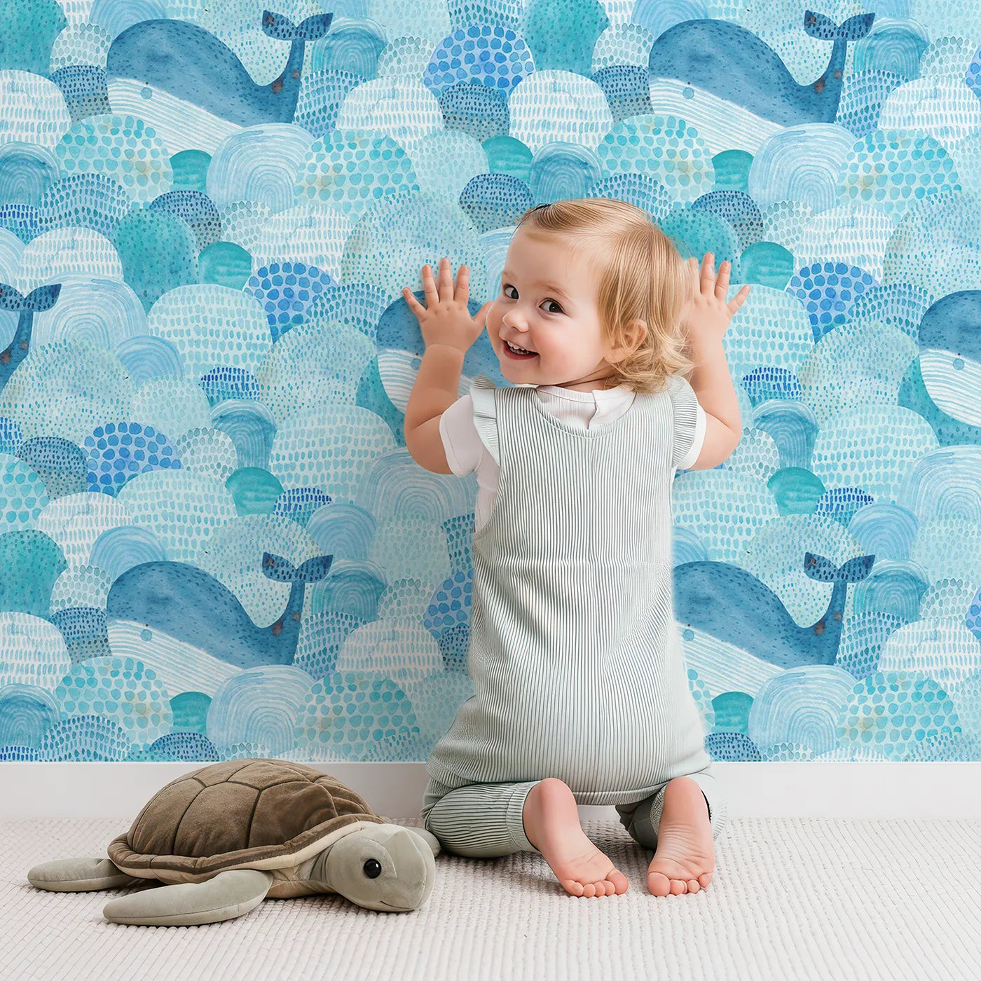 Lovely child standing in front of Whimsy Tots Abstract Watercolor Whales Wallpaper with whale, ocean, sea, watercolor, abstract in design.