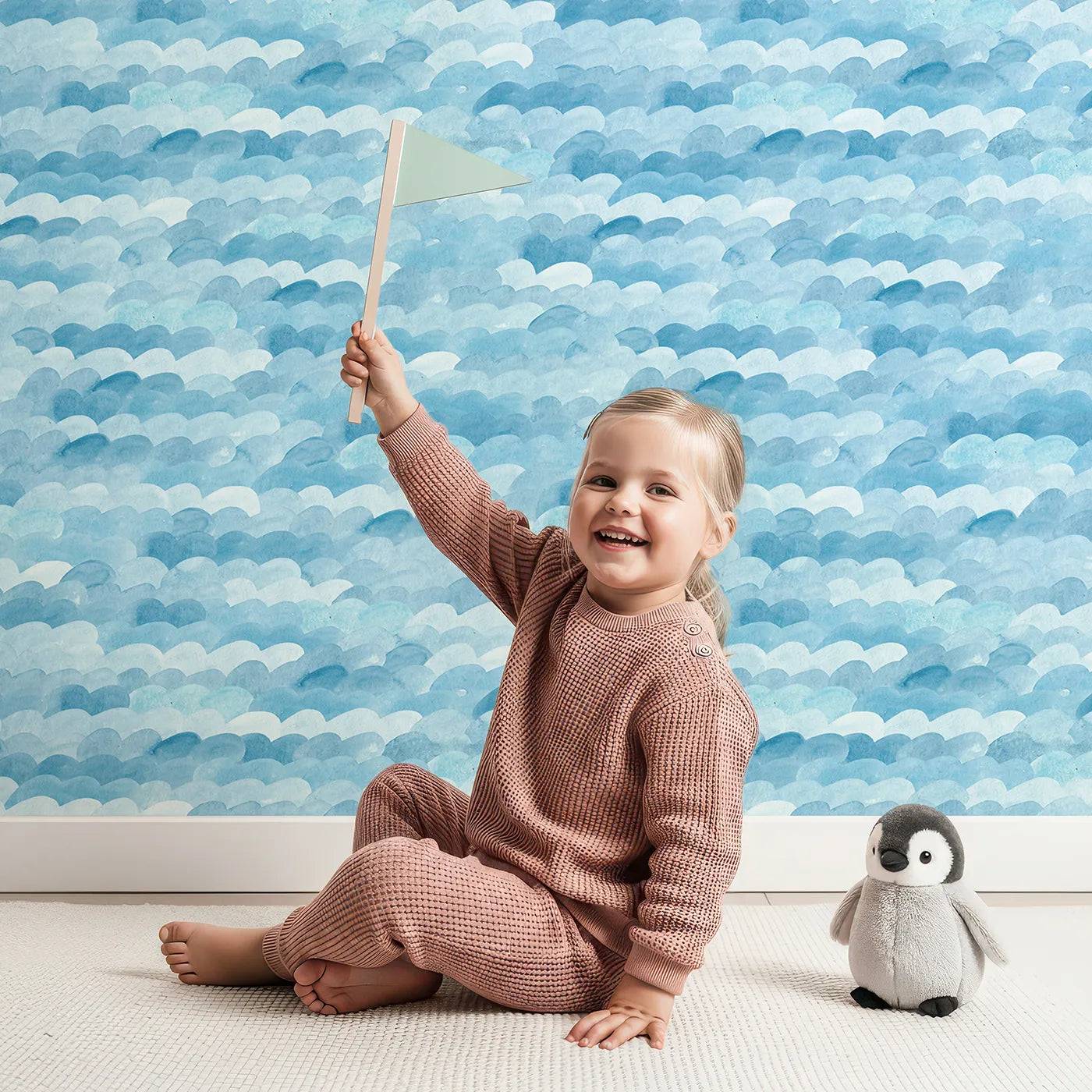 Lovely child standing in front of Whimsy Tots Abstract Blue Watercolor Waves Wallpaper with wave, watercolor, blue, abstract, ocean in design.
