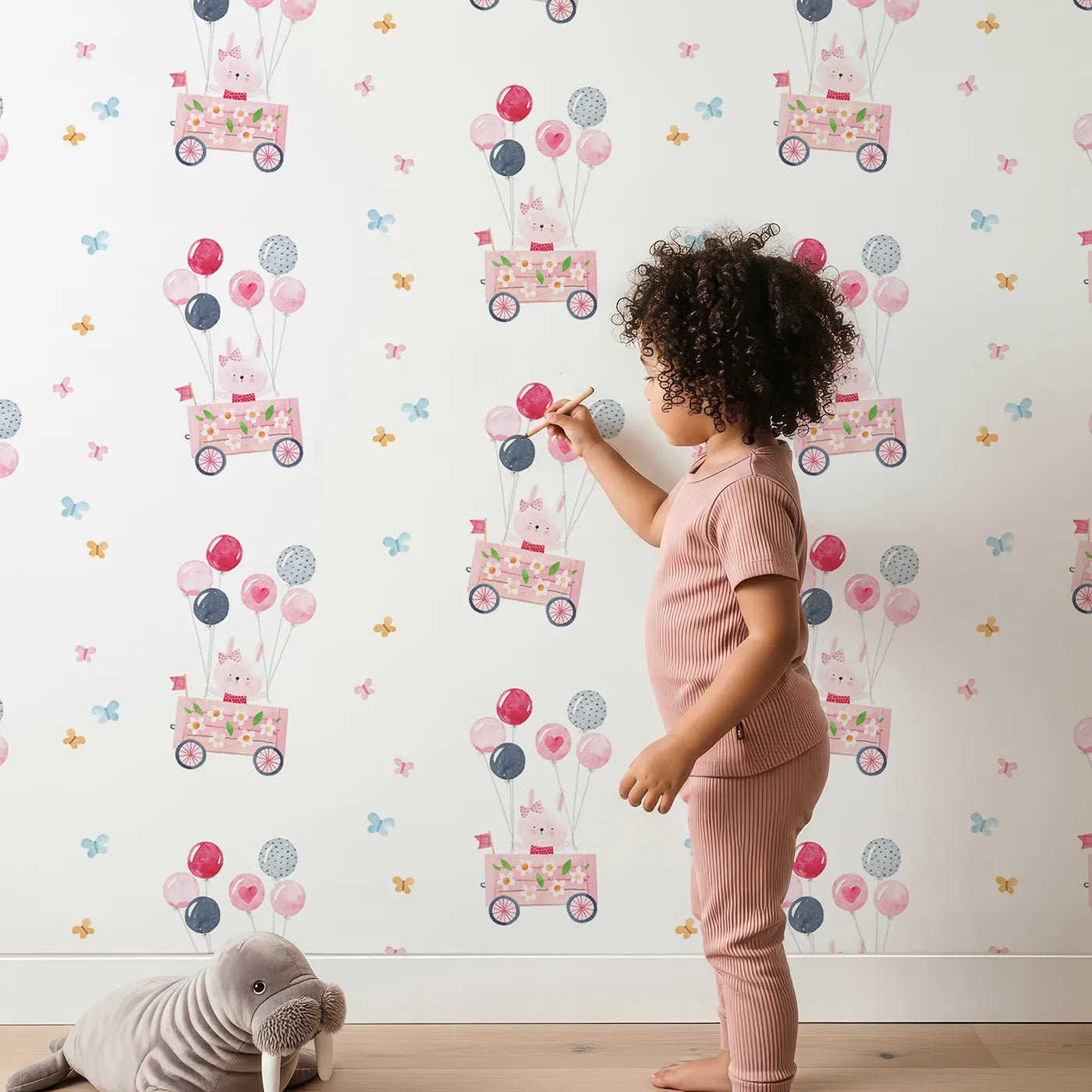Lovely child standing in front of Whimsy Tots Bunny Balloon Parade Wallpaper with bunny, rabbit, balloon, butterfly, watercolor in design.