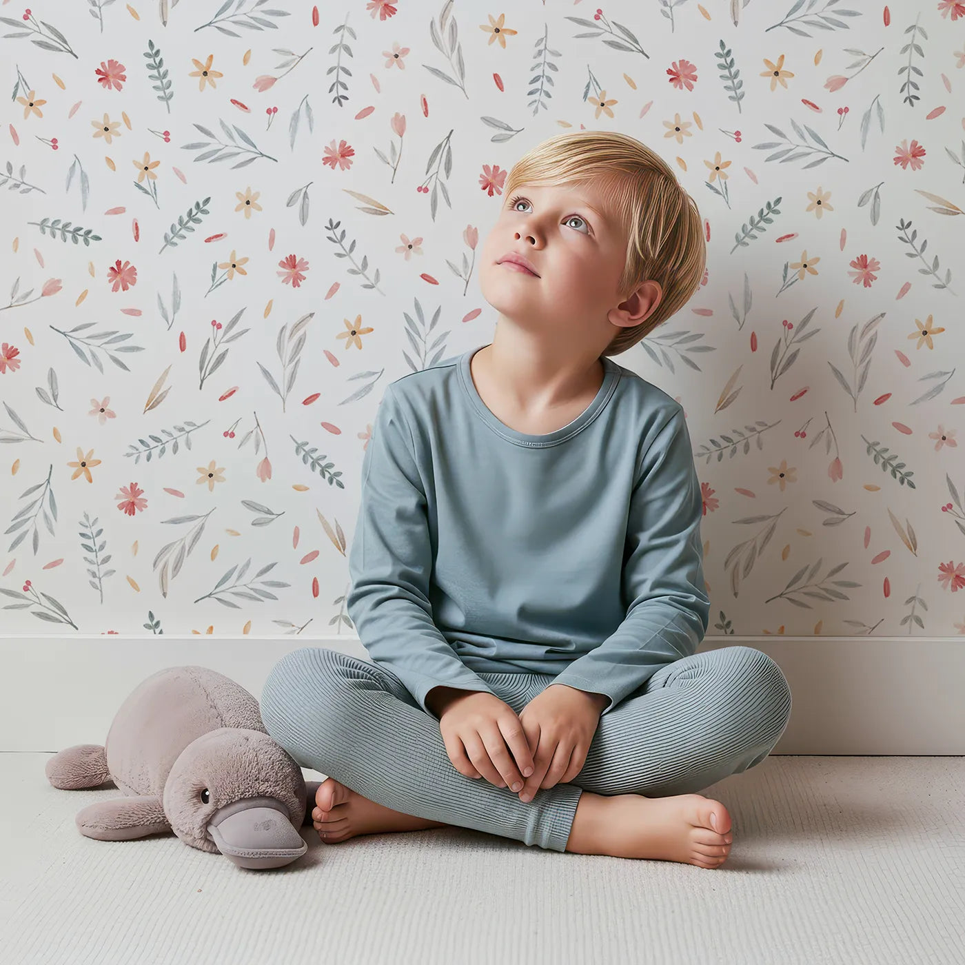 Lovely child standing in front of Whimsy Tots Delicate Watercolor Meadow Wallpaper with flower, floral, watercolor, minimalist, botanical in design.