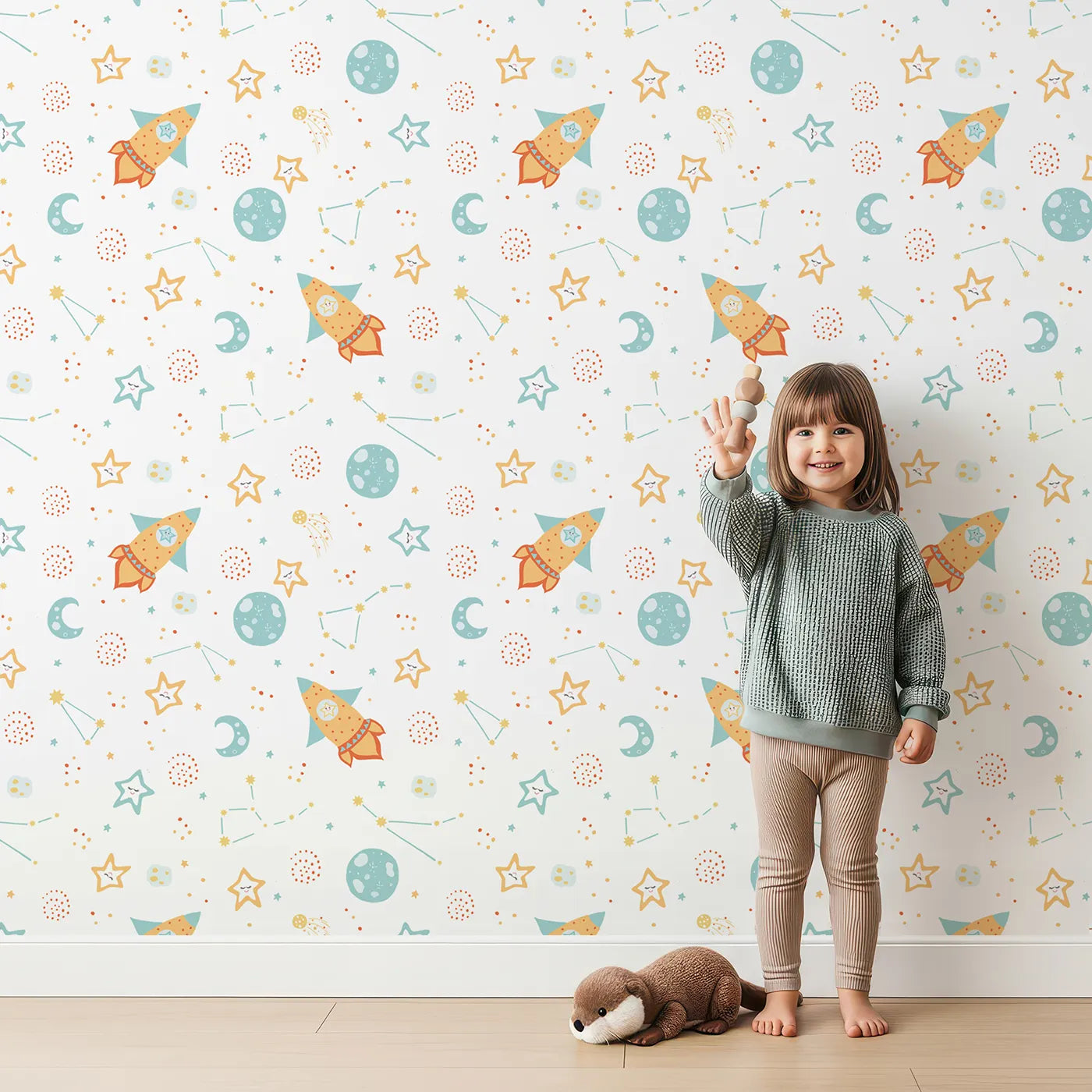 Lovely child standing in front of Whimsy Tots Pastel Space Pals Wallpaper with space, rocket, planet, star, cute in design.