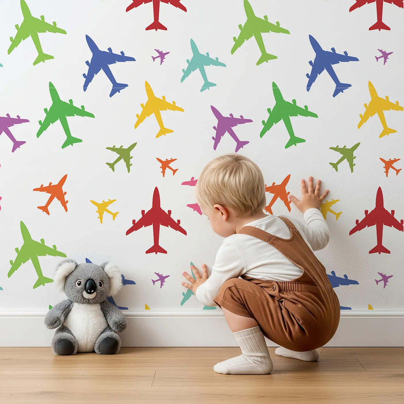 Lovely child standing in front of Whimsy Tots Rainbow Airplane Silhouettes Wallpaper with plane, airplane, silhouette, rainbow, colorful in design.