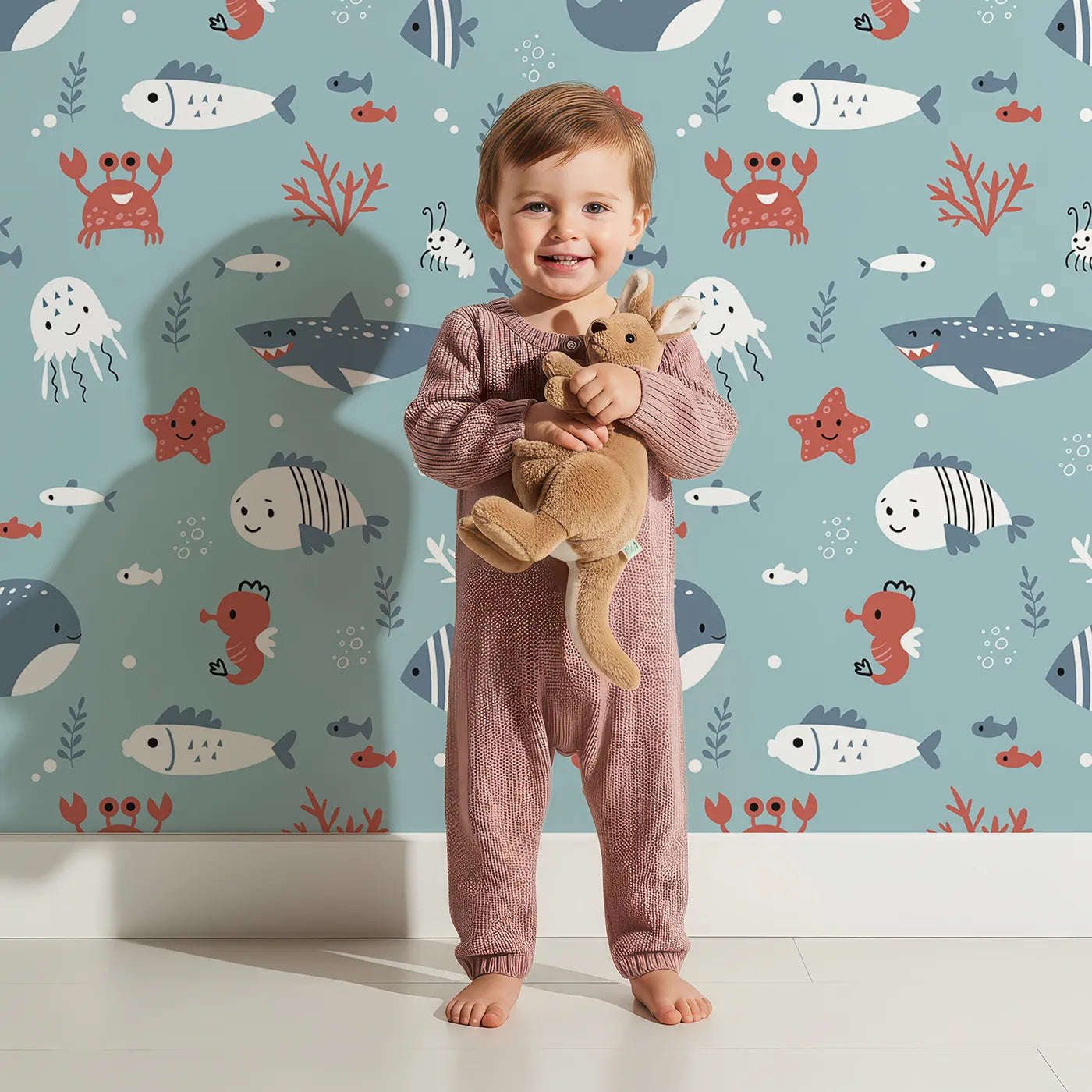Lovely child standing in front of Whimsy Tots Happy Ocean Friends Wallpaper in Blue with ocean, sea, fish, shark, whale in design.