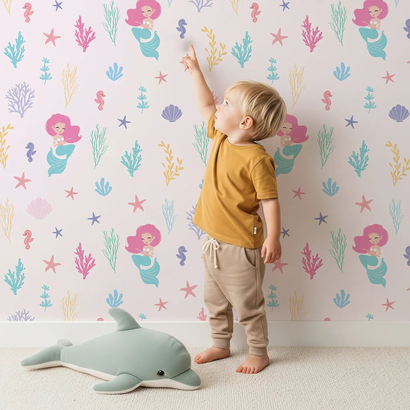 Lovely child standing in front of Whimsy Tots Pastel Mermaid Garden Wallpaper with mermaid, coral, starfish, shell, ocean in design.
