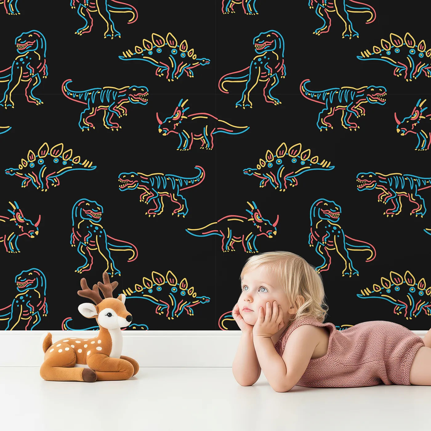 Lovely child standing in front of Whimsy Tots Neon Dinosaur Skeletons Wallpaper with dinosaur, neon, skeleton, glow, black in design.