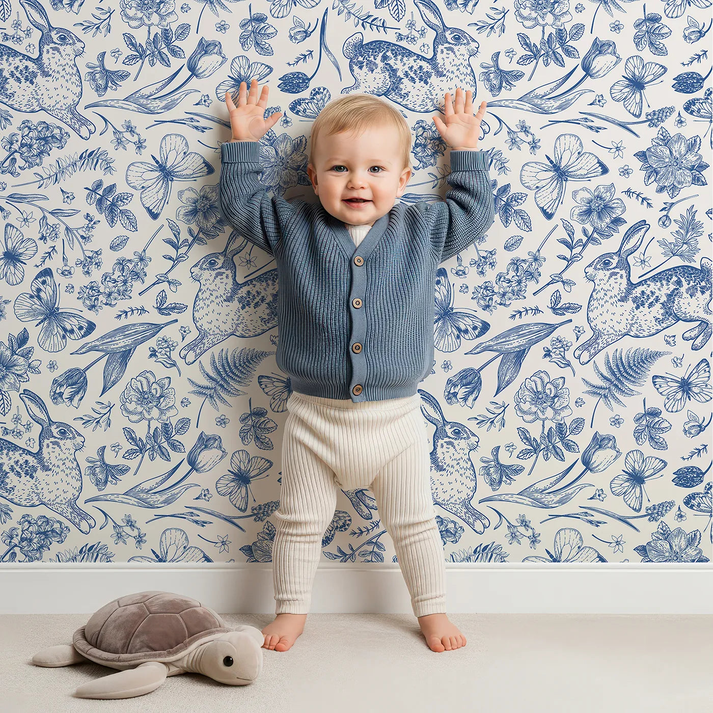 Lovely child standing in front of Whimsy Tots Vintage Rabbit Toile Wallpaper in Blue with rabbit, bunny, toile, vintage, floral in design.
