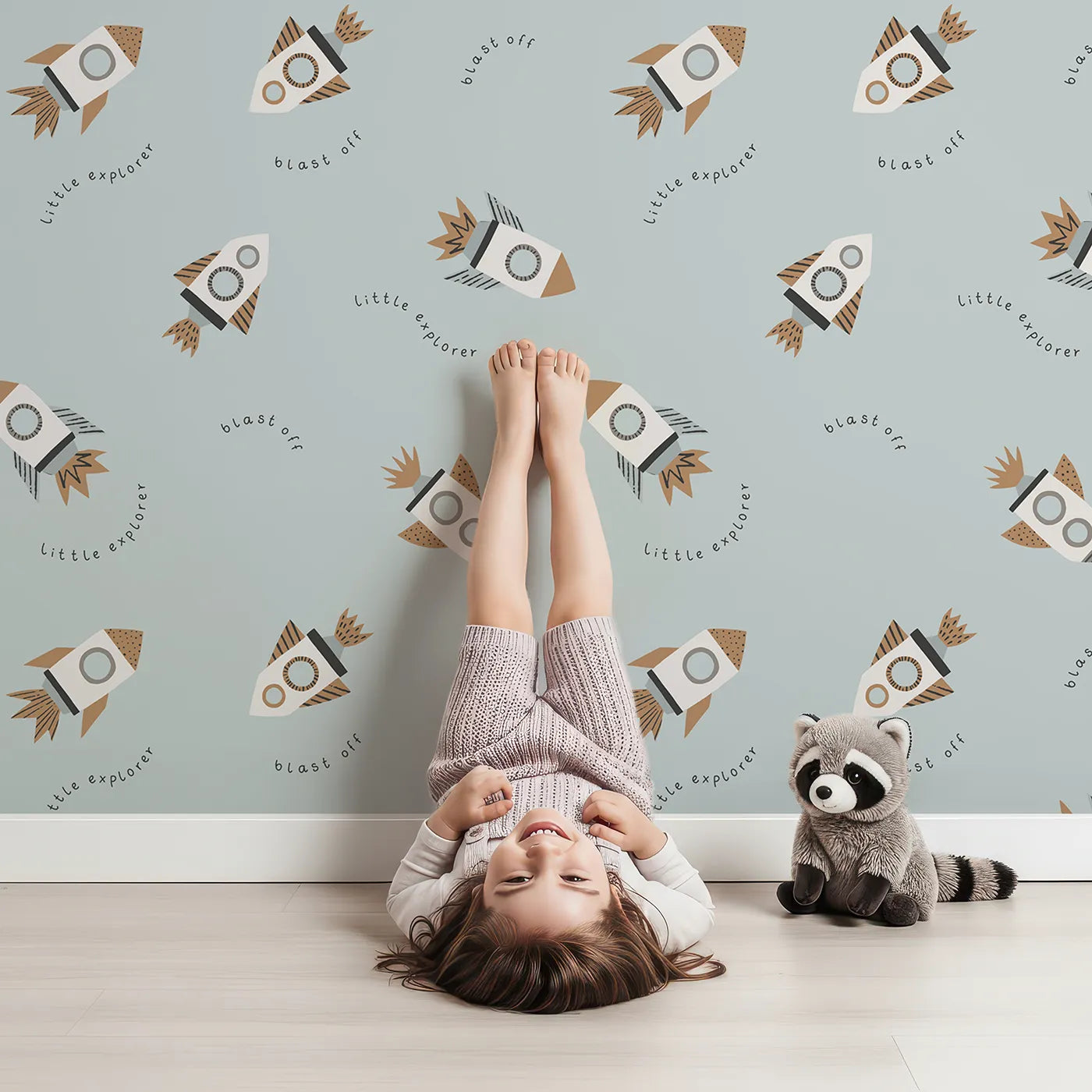 Lovely child standing in front of Whimsy Tots Little Explorer Rocket Wallpaper with rocket, space, explorer, blast off, minimalist in design.