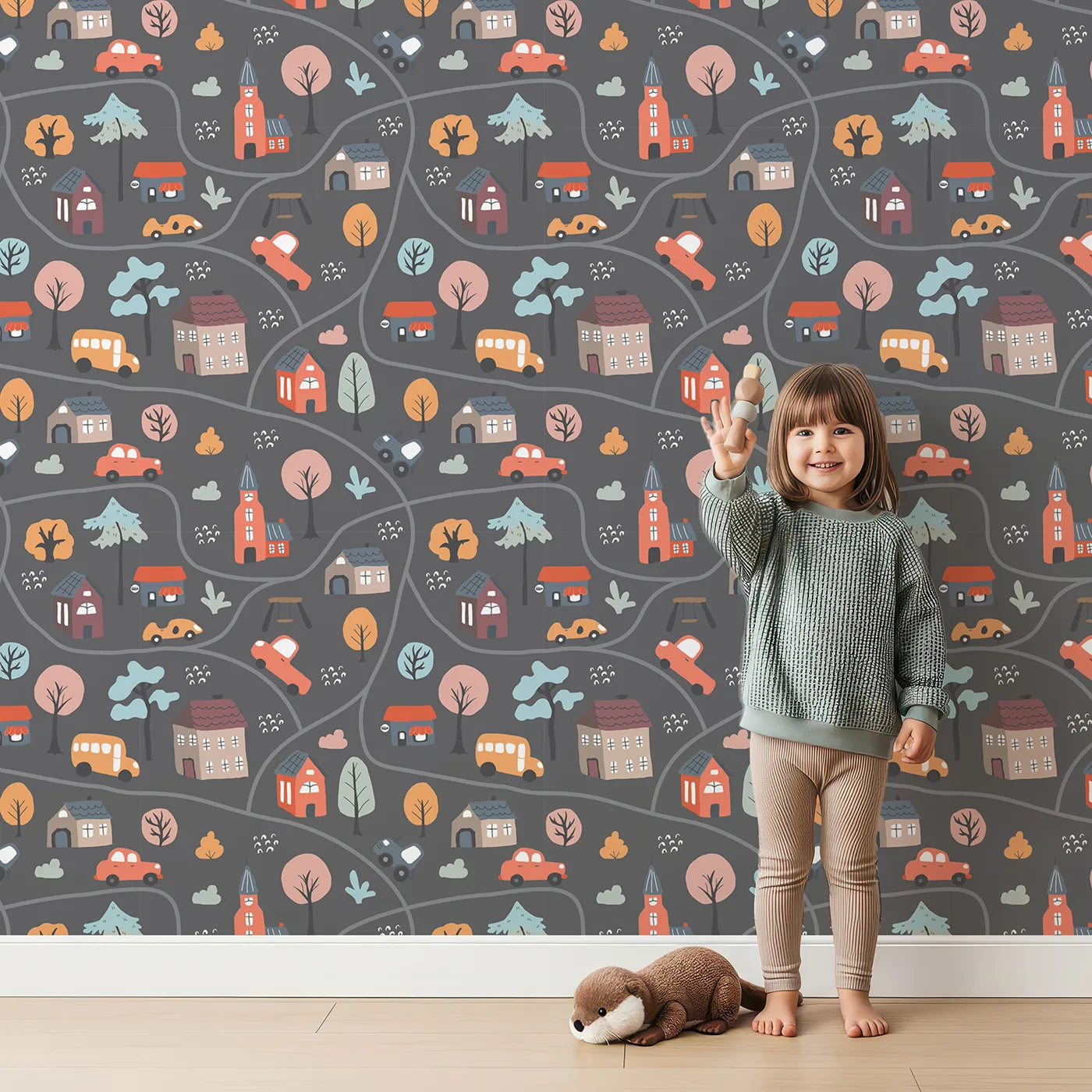 Lovely child standing in front of Whimsy Tots Cozy Town Map Wallpaper in Gray with map, city, house, road, car in design.