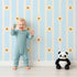 Lovely child standing in front of Whimsy Tots Daisy Lane Stripe Wallpaper in Blue with daisy, flower, stripe in design. Lovely child standing in front of Whimsy Tots Daisy Lane Stripe Wallpaper in Blue with daisy, flower, stripe in design.