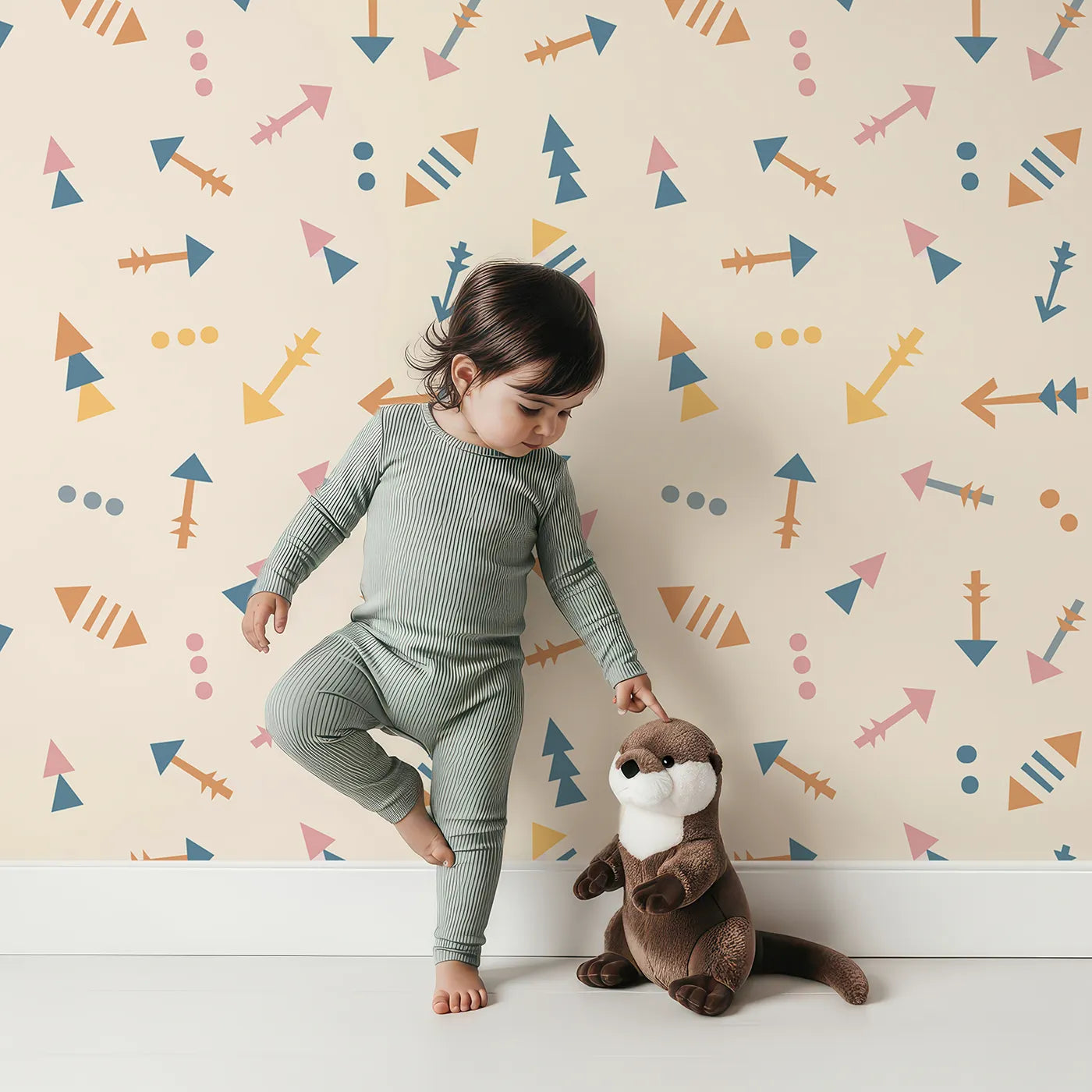 Lovely child standing in front of Whimsy Tots Boho Arrows Wallpaper in Cream with arrow, triangle, dot in design.