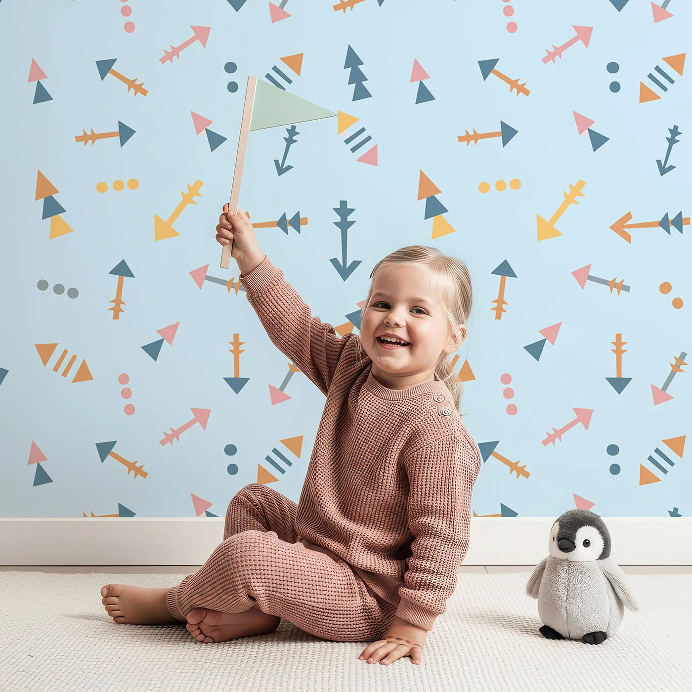 Lovely child standing in front of Whimsy Tots Boho Arrows Wallpaper in Blue with arrow, triangle, dot in design.