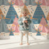 Lovely child standing in front of Whimsy Tots Teepee Parade Wallpaper in Cream with teepee, arrow, triangle, tent in design. Lovely child standing in front of Whimsy Tots Teepee Parade Wallpaper in Cream with teepee, arrow, triangle, tent in design.