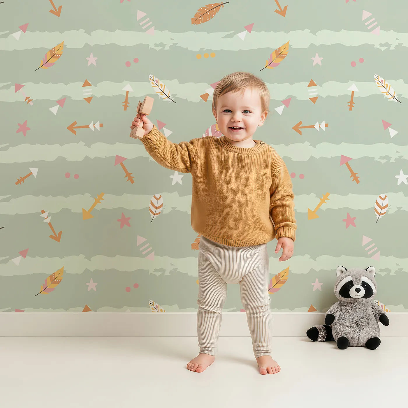 Lovely child standing in front of Whimsy Tots Tribal Sky Dance Wallpaper in Green with arrow, feather, star, stripe in design.