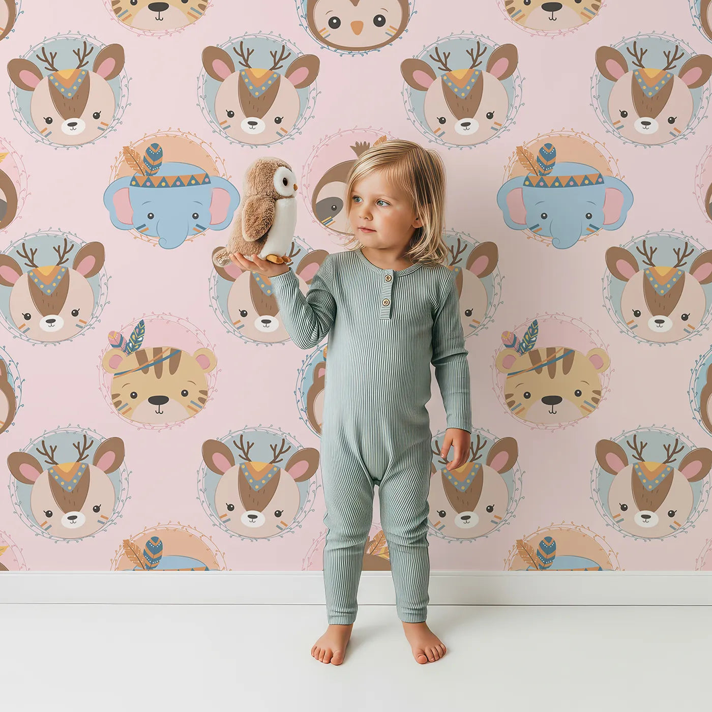 Lovely child standing in front of Whimsy Tots Woodland Royalty Parade Wallpaper in Pink with bear, deer, elephant, tiger, feather, wreath, crown in design.