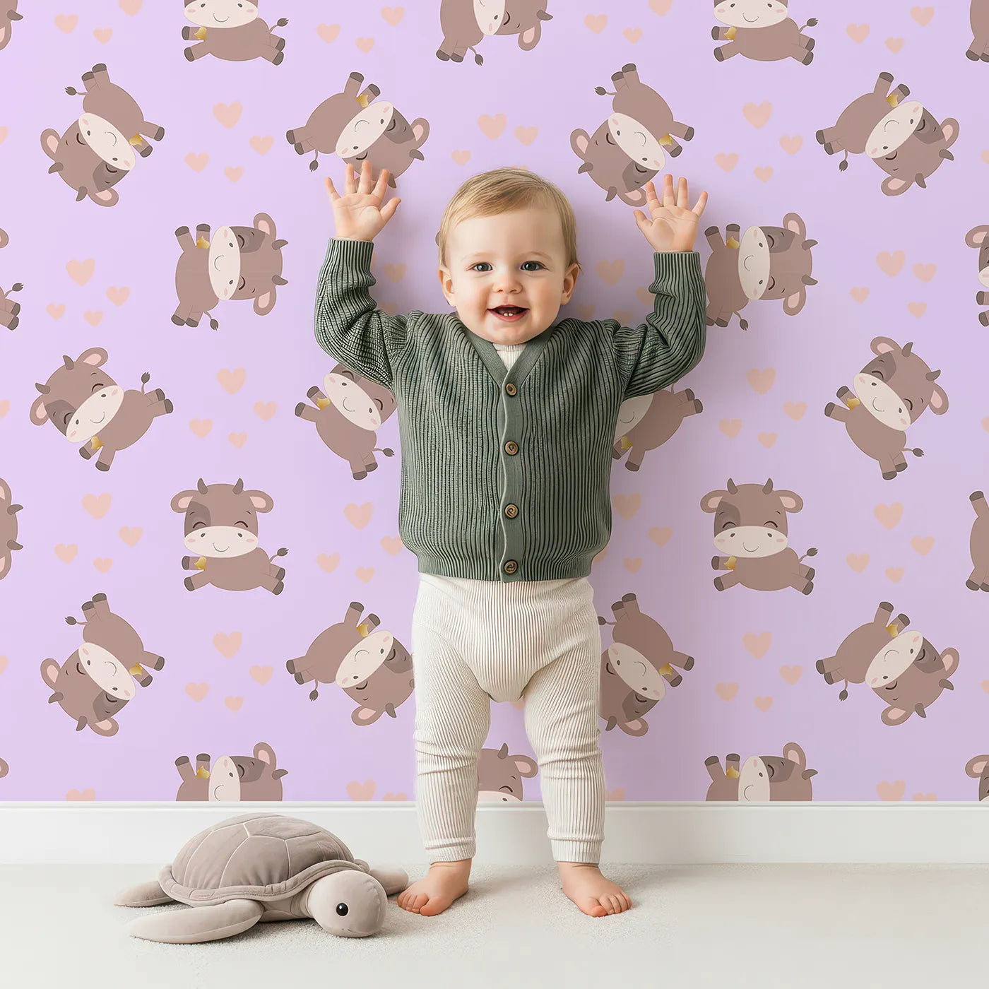 Lovely child standing in front of Whimsy Tots Moo Moo Love Wallpaper in Purple with cow, heart, bell in design.