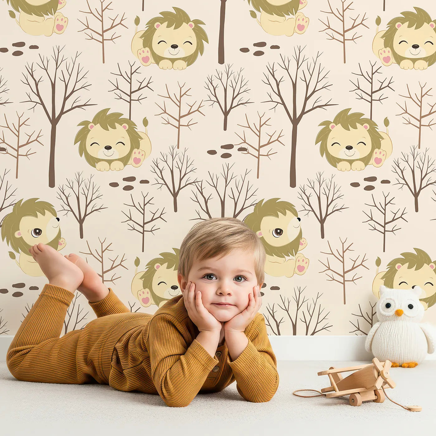 Lovely child standing in front of Whimsy Tots Little Lion Nap Wallpaper in Cream with lion, tree, footprint in design.