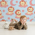 Lovely child standing in front of Whimsy Tots Starry Safari Dreams Wallpaper in Blue with lion, cloud, moon, star in design. Lovely child standing in front of Whimsy Tots Starry Safari Dreams Wallpaper in Blue with lion, cloud, moon, star in design.
