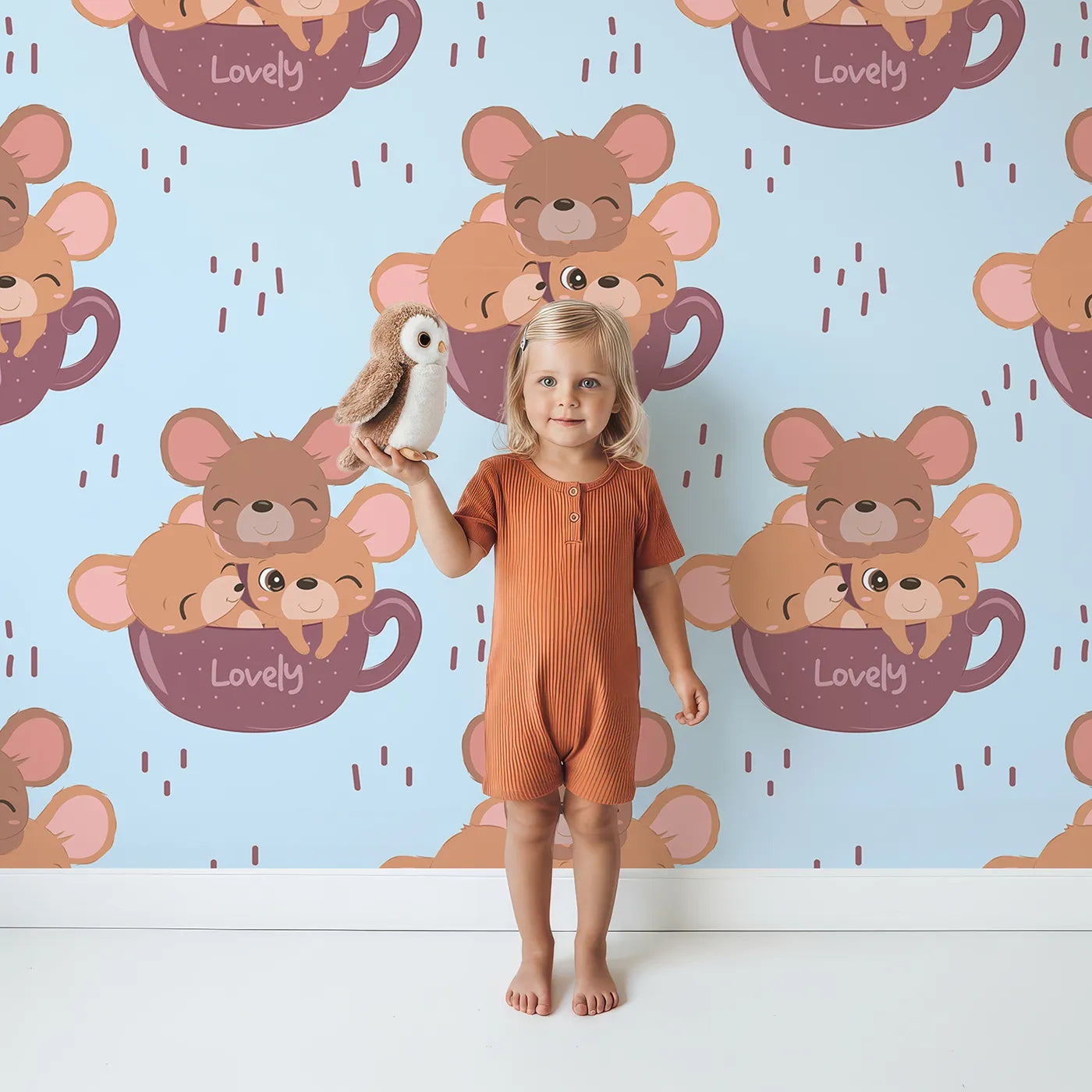 Lovely child standing in front of Whimsy Tots Lovely Tea Mice Wallpaper in Blue with mouse, cup, sprinkle in design.