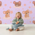 Lovely child standing in front of Whimsy Tots Starry Cloud Mouse Wallpaper in Purple with mouse, cloud, balloon, star in design. Lovely child standing in front of Whimsy Tots Starry Cloud Mouse Wallpaper in Purple with mouse, cloud, balloon, star in design.