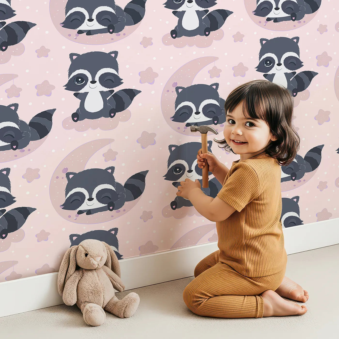 Lovely child standing in front of Whimsy Tots Moonbeam Raccoon Dreams Wallpaper in Pink with raccoon, moon, cloud, star in design.