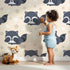 Lovely child standing in front of Whimsy Tots Raccoon Dream Stars Wallpaper in Cream with raccoon, star in design. Lovely child standing in front of Whimsy Tots Raccoon Dream Stars Wallpaper in Cream with raccoon, star in design.