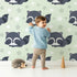 Lovely child standing in front of Whimsy Tots Raccoon Dream Stars Wallpaper in Green with raccoon, star in design. Lovely child standing in front of Whimsy Tots Raccoon Dream Stars Wallpaper in Green with raccoon, star in design.
