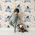 Lovely child standing in front of Whimsy Tots Zebra Snuggle Smiles Wallpaper in Beige with zebra, heart, face in design. Lovely child standing in front of Whimsy Tots Zebra Snuggle Smiles Wallpaper in Beige with zebra, heart, face in design.