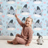 Lovely child standing in front of Whimsy Tots Zebra Snuggle Smiles Wallpaper in Blue with zebra, heart, face in design. Lovely child standing in front of Whimsy Tots Zebra Snuggle Smiles Wallpaper in Blue with zebra, heart, face in design.