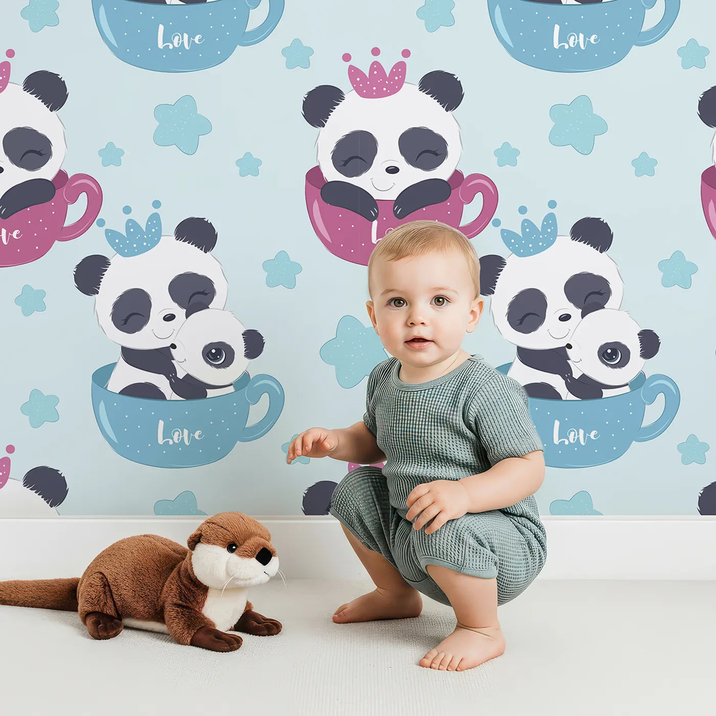 Lovely child standing in front of Whimsy Tots Cuddle Cup Panda Wallpaper in Blue with panda, cup, star, crown in design.