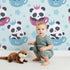 Lovely child standing in front of Whimsy Tots Cuddle Cup Panda Wallpaper in Blue with panda, cup, star, crown in design. Lovely child standing in front of Whimsy Tots Cuddle Cup Panda Wallpaper in Blue with panda, cup, star, crown in design.