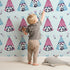 Lovely child standing in front of Whimsy Tots Tribal Camp Panda Wallpaper in Blue with panda, teepee, feather, arrow, dot in design. Lovely child standing in front of Whimsy Tots Tribal Camp Panda Wallpaper in Blue with panda, teepee, feather, arrow, dot in design.