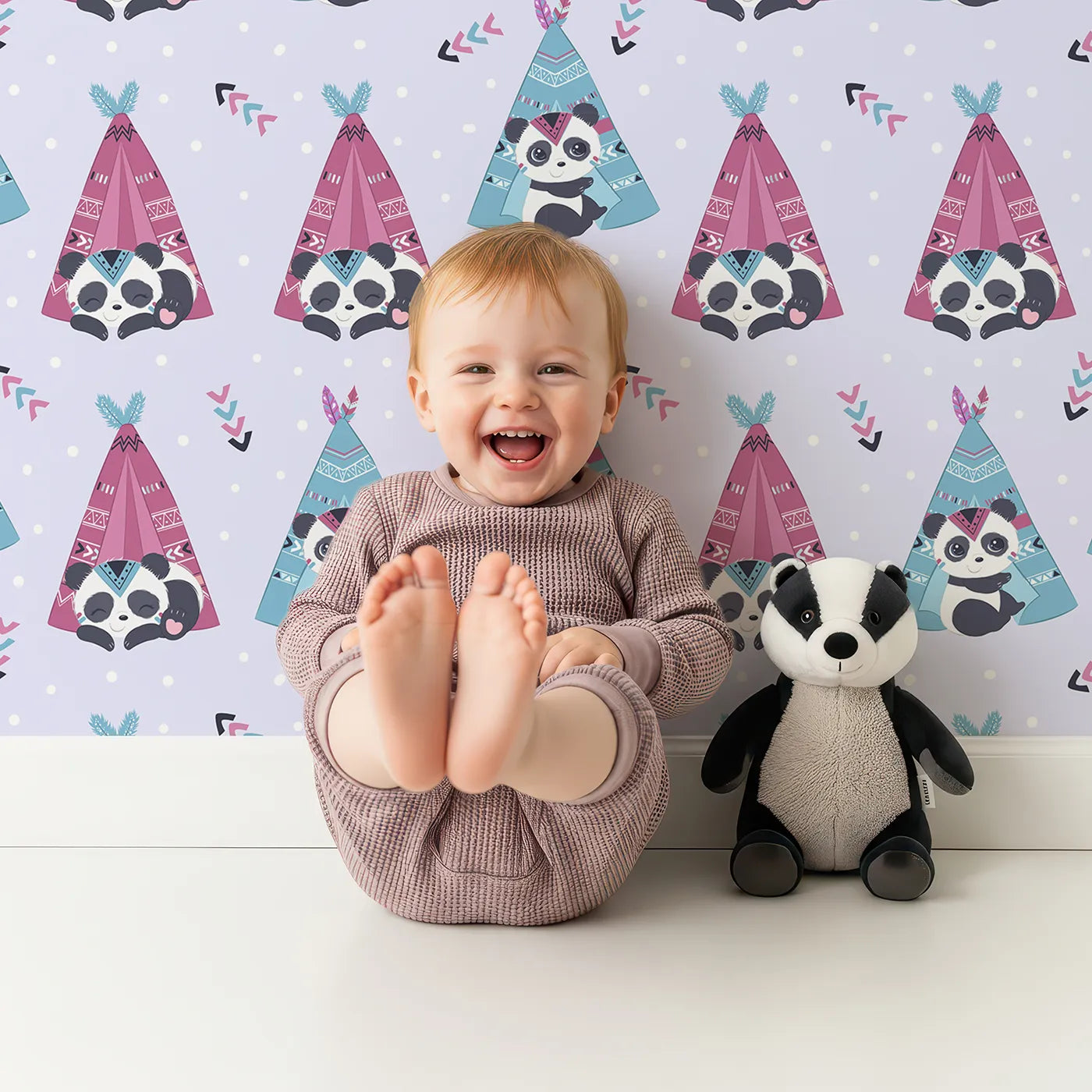 Lovely child standing in front of Whimsy Tots Tribal Camp Panda Wallpaper in Lavender with panda, teepee, feather, arrow, dot in design.