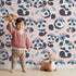 Lovely child standing in front of Whimsy Tots Tribal Hug Panda Wallpaper in Pink with panda, feather, headband, hug, leaf in design. Lovely child standing in front of Whimsy Tots Tribal Hug Panda Wallpaper in Pink with panda, feather, headband, hug, leaf in design.