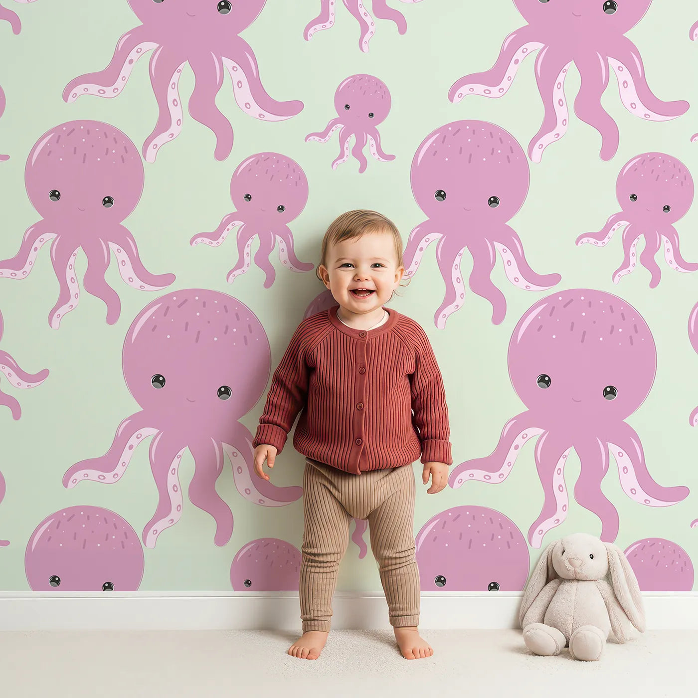 Lovely child standing in front of Whimsy Tots Ocean Bubbles Octopus Wallpaper in Mint Green with octopus, tentacle, dot, sea in design.