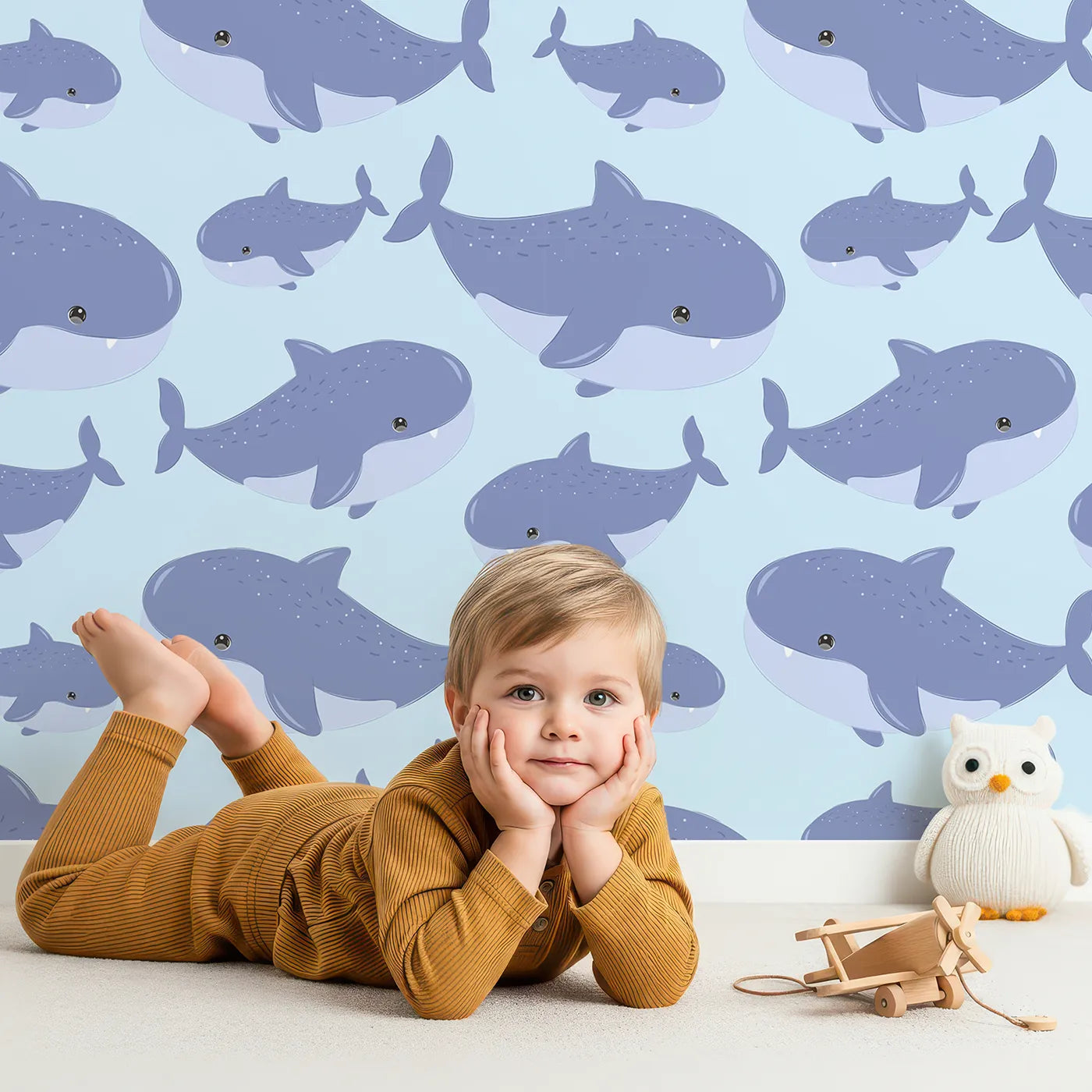 Lovely child standing in front of Whimsy Tots Whale Shark Wiggles Wallpaper in Sky Blue with shark, whale shark, spot, sea in design.